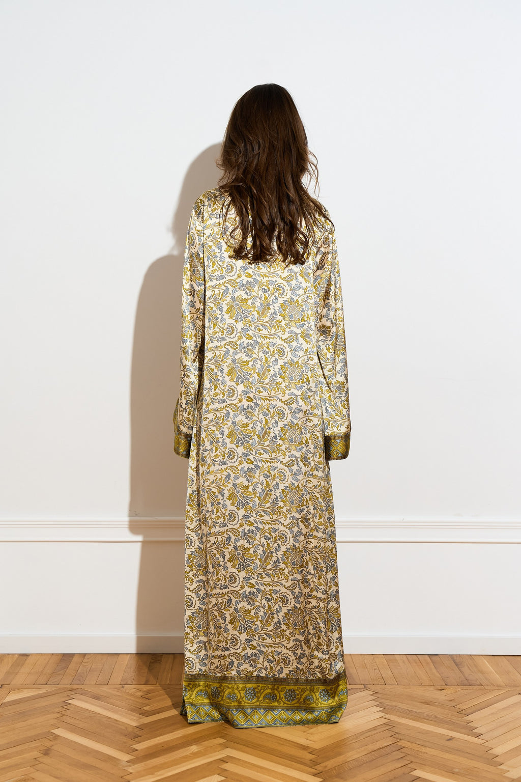 Long sleeved silk dress with a an olive floral pattern from the back 