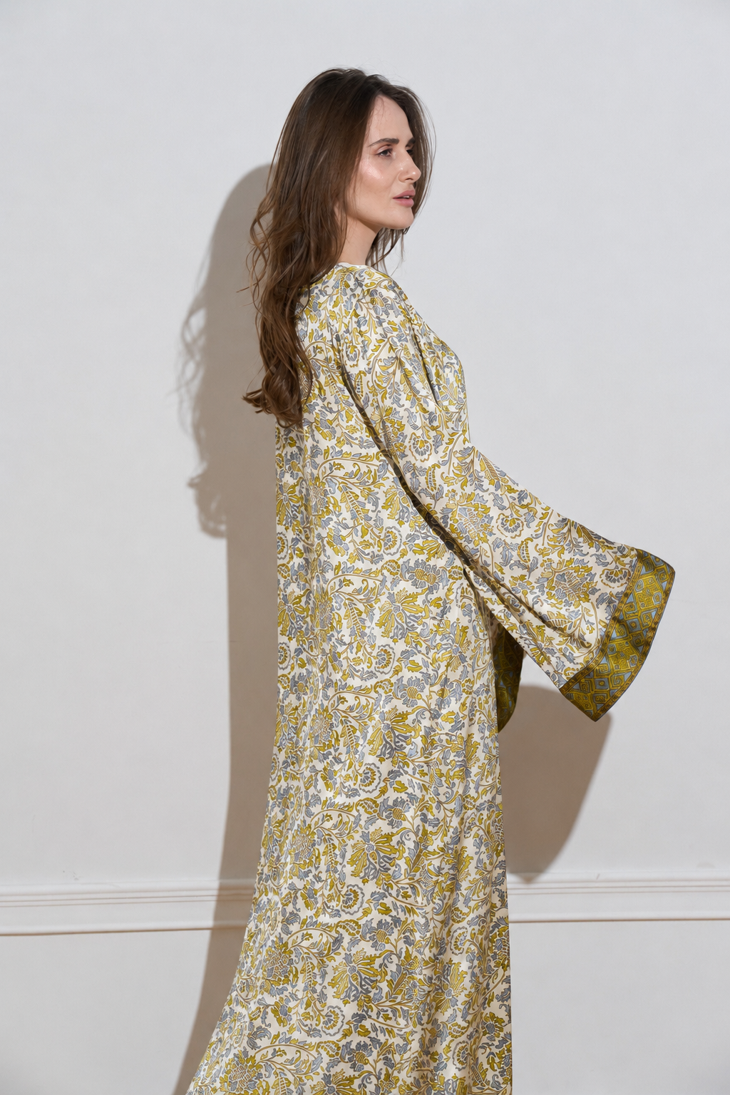 Long sleeved silk dress with a an olive floral pattern from the side 