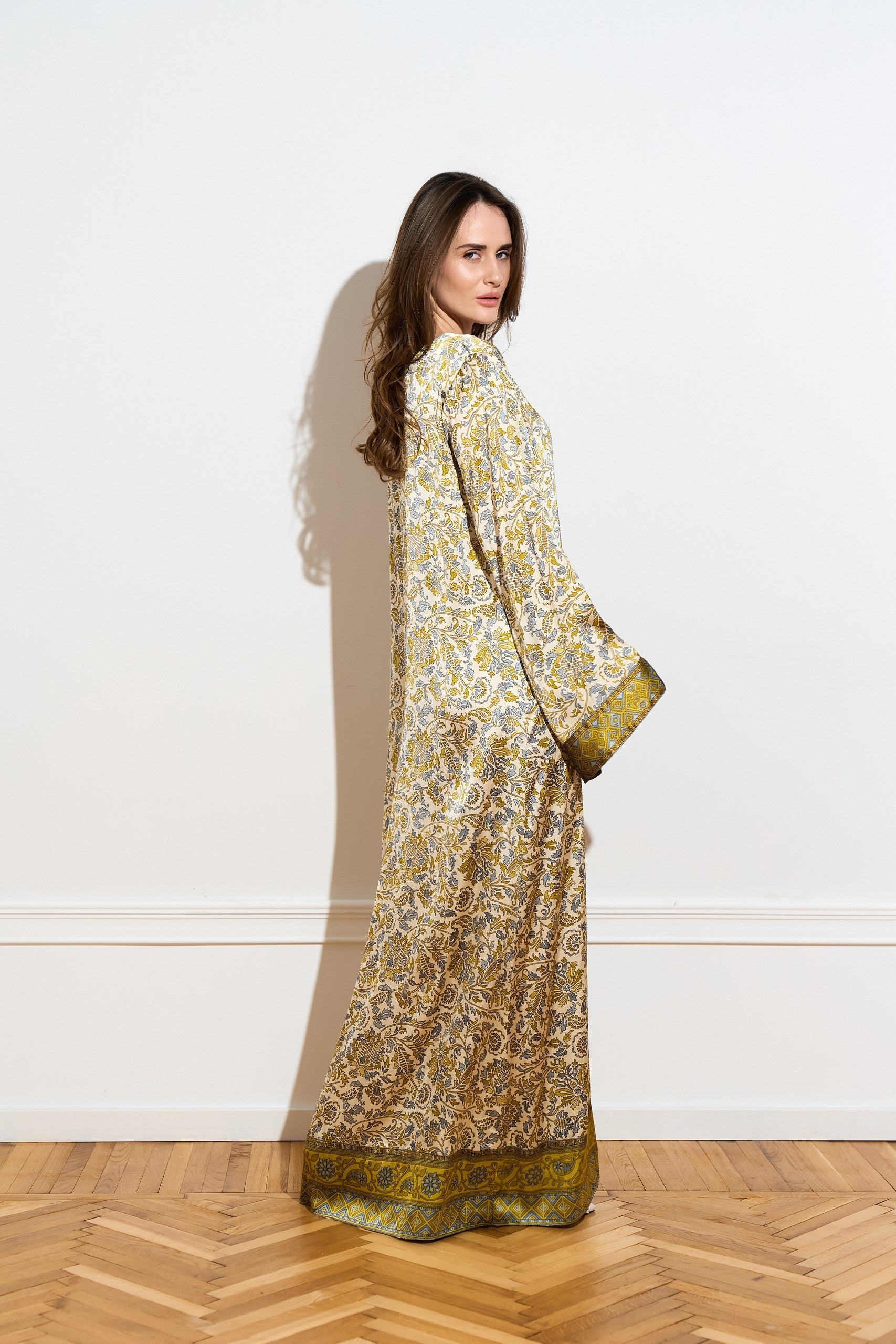 Long sleeved silk dress with a an olive floral pattern from the side 