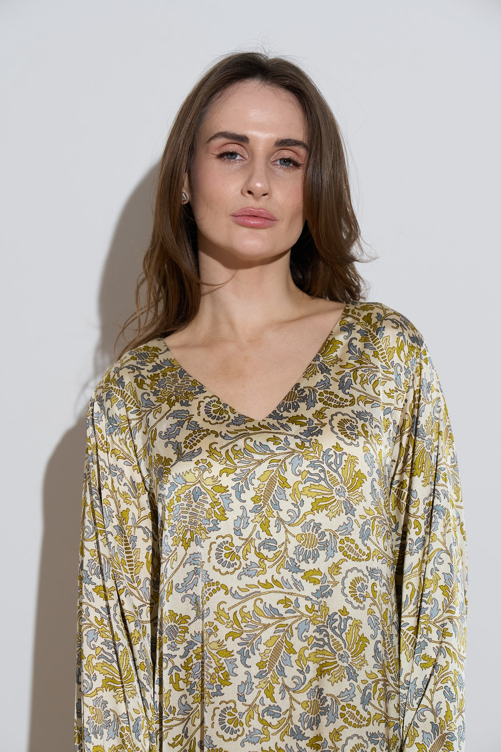 Long sleeved silk dress with a an olive floral pattern close up 