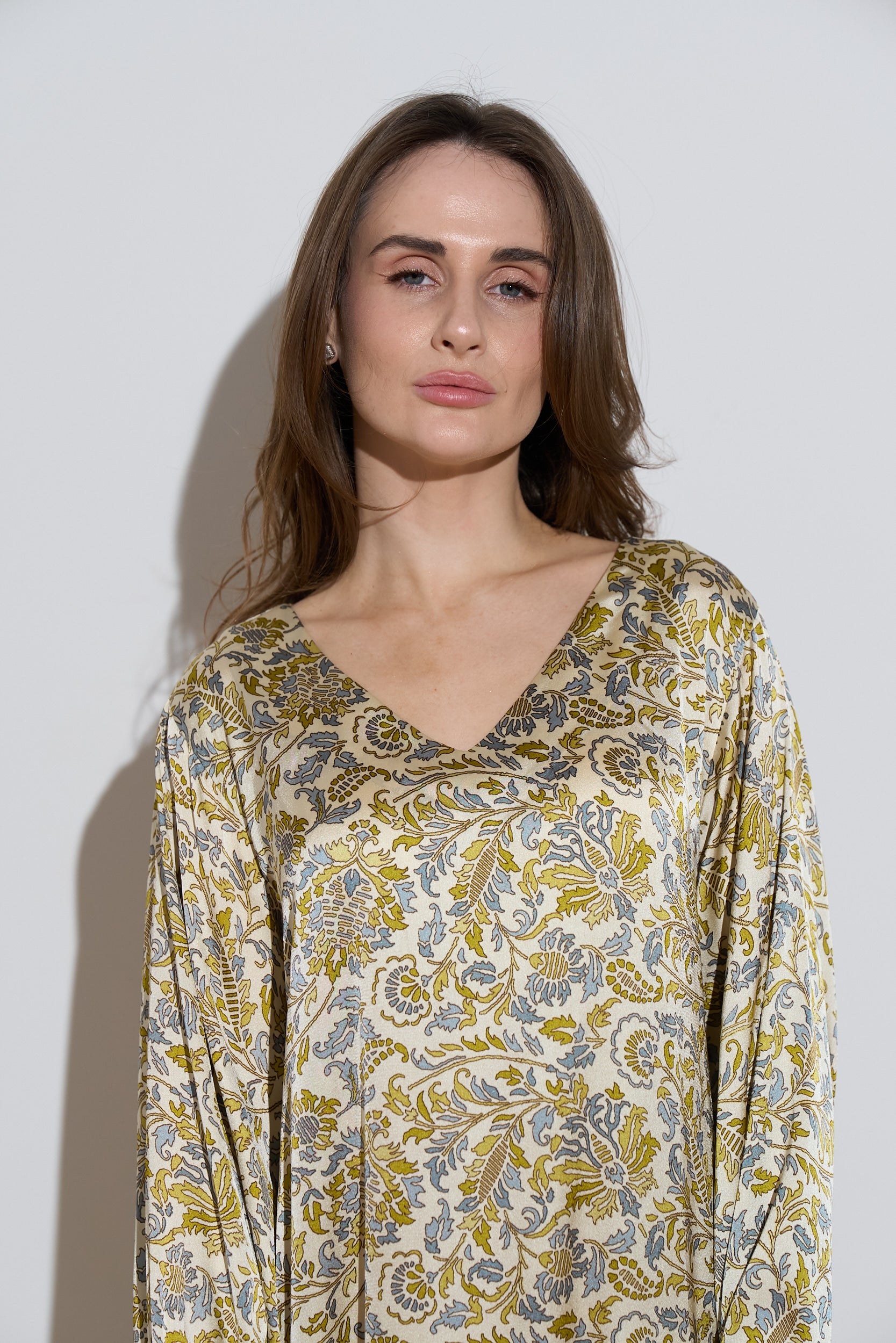 Long sleeved silk dress with a an olive floral pattern close up 